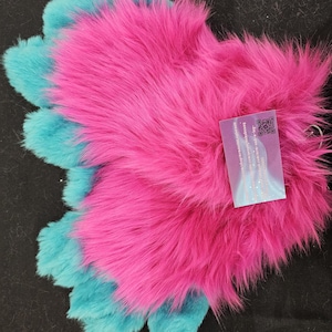 May include: A pair of pink and teal furry hand paws. The paws have three toes each and are made of soft, fluffy fur.