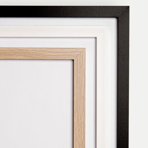 May include: A triple matted picture frame with a black outer frame, a white middle frame, and a natural wood inner frame.