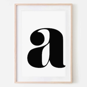May include: A black and white printable art print featuring the letter 'a' in a bold, stylized font. The letter is centered on a white background and framed in a light wood frame.