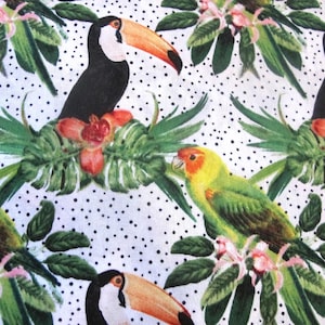 May include: A repeating pattern featuring toucans and parrots amidst tropical foliage and flowers. The birds are black, green, yellow, and orange, set against a white background with black polka dots. The design includes green leaves and pink flowers.