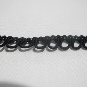 May include: Black elastic trim with a decorative chain-like pattern. The trim is made of a soft, flexible material and is perfect for adding a touch of elegance to any project.