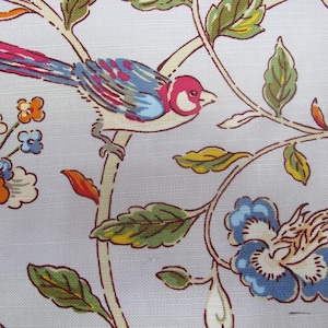 May include: A fabric with a repeating pattern of a colorful bird perched on a branch with leaves and flowers. The bird has pink, blue, and red feathers. The flowers are orange and blue.