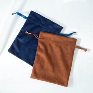 Pode incluir: Duas bolsas de cord&atilde;o de veludo, uma azul marinho e outra marrom. As bolsas s&atilde;o feitas de veludo macio e luxuoso e t&ecirc;m um design simples e elegante.