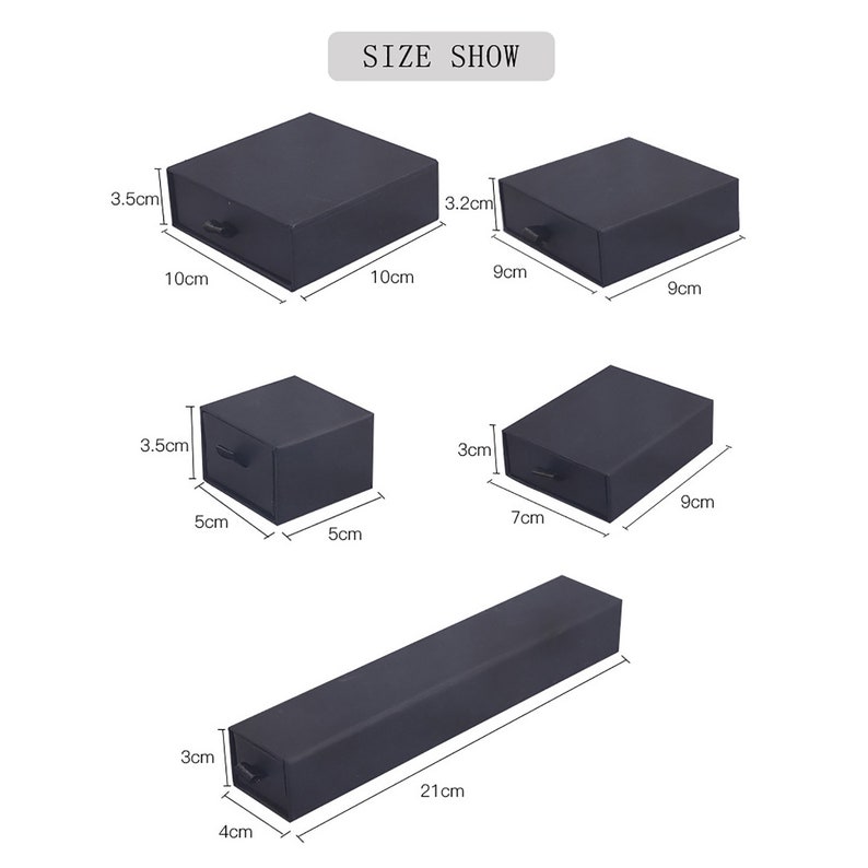 Op de afbeelding: Vier zwarte dozen met laden in verschillende maten. De dozen meten 10 cm x 10 cm, 9 cm x 9 cm, 5 cm x 5 cm en 7 cm x 9 cm. Een lange zwarte doos meet 21 cm x 4 cm.