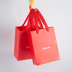 May include: Two red shopping bags with white text. The bag on the left says "Vin" and the bag on the right says "Vmknde".