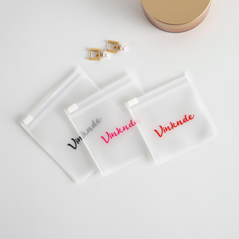 Puede incluir: Tres bolsas de pl&aacute;stico transparentes con cremallera con la palabra "Vinknde" impresa en negro, rosa y rojo.