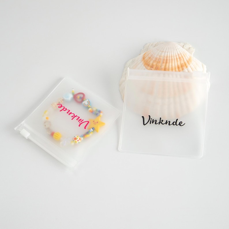 Puede incluir: Dos bolsas de pl&aacute;stico transparente con cierre de cremallera con la palabra "Vinknde" impresa en ellas. Una bolsa contiene un brazalete de cuentas de colores con un dije de estrella.