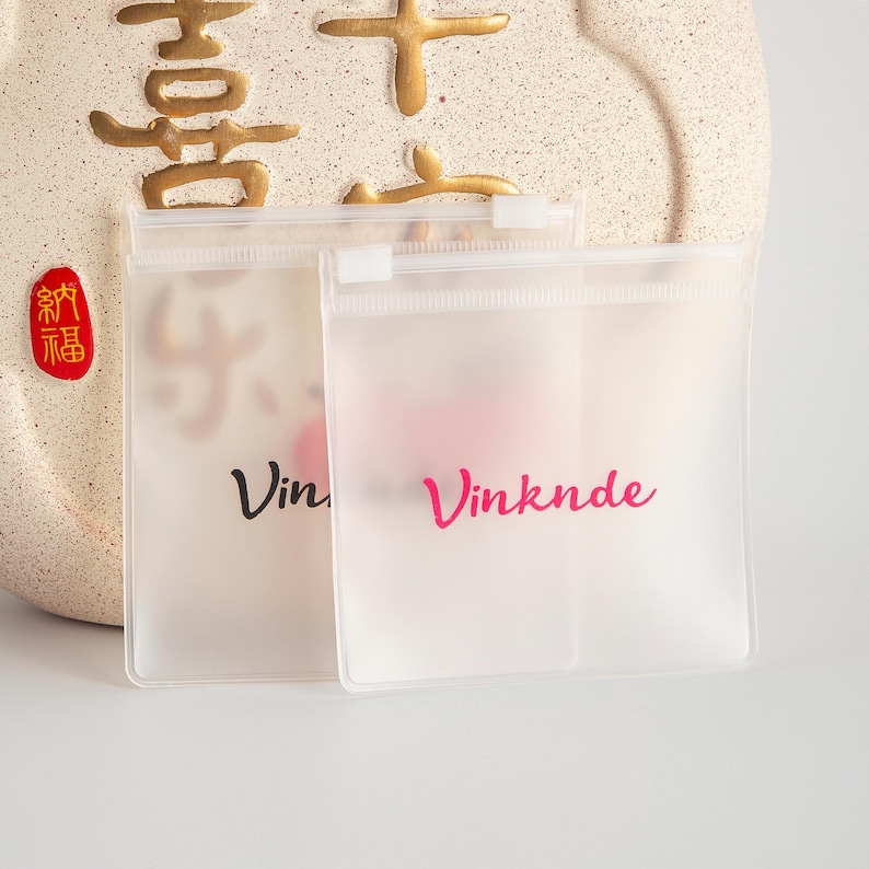 Puede incluir: Dos bolsas de pl&aacute;stico transparentes con cierre de cremallera, con la palabra "Vinknde" impresa en rosa en una bolsa y "Vin" impresa en negro en la otra bolsa.