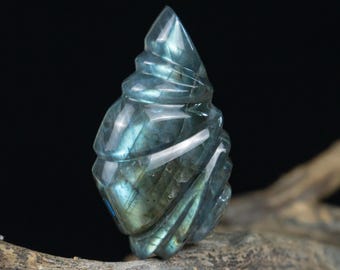 May include: A blue labradorite crystal carved into a spiral shape. The crystal is iridescent and has a smooth, polished finish.