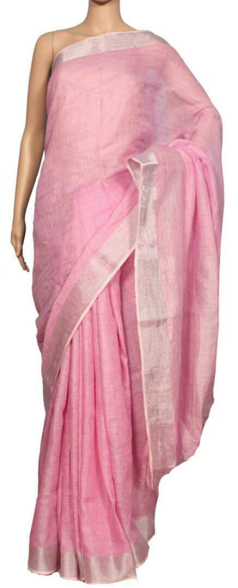 May include: A pink linen saree with a silver border. The saree is draped over a mannequin.