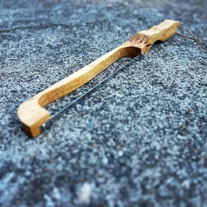 May include: A wooden cheese knife with a stainless steel blade. The handle is made of natural wood with a unique grain pattern.
