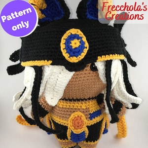 May include: Crochet pattern for a plush toy with a black, yellow, and blue headdress, white hair, and a brown body. The toy is wearing a yellow, orange, and blue outfit. The text "Frecchola's Creations" is visible in the image.