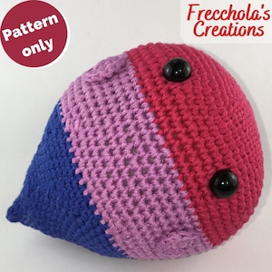 Può includere: Un peluche a forma di lacrima lavorato a uncinetto con strisce blu, viola e rosa. Il peluche ha due occhi neri a bottone.