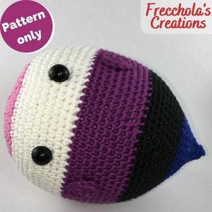 May include: A crocheted plushie shaped like a teardrop with pink, white, purple, black, and blue stripes. The plushie has two black eyes.