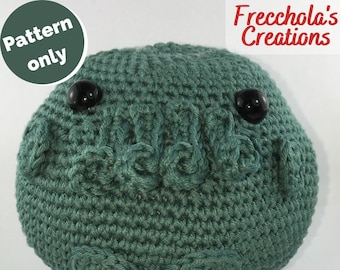 May include: A green crocheted amigurumi toy with black eyes. The toy has a round shape and a textured surface.