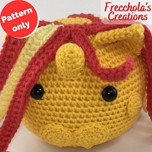 Puede incluir: Una cabeza de unicornio tejida en amarillo con detalles rojos y amarillos. El unicornio tiene ojos negros de botón y un pequeño cuerno. El texto "Pattern only" está en un círculo rojo en la esquina superior izquierda. El texto "Frecchola's Creations" está en la esquina superior derecha.