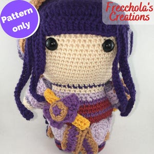 May include: Crocheted doll with purple hair, a purple, red, and brown dress, and a yellow flower. The doll has black eyes and a cream-colored face. The doll is standing on a white surface. The text "Pattern only" is in a purple circle in the top left corner of the image. The text "Frechcola's Creations" is in the top right corner of the image.