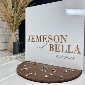 Op de afbeelding: Witte acrylbox met gouden opschrift "Jemeson en Bella 10.11.2022".
