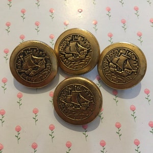 May include: Four gold-colored metal buttons with a raised design of a ship with the text "Santa Maria" around the edge.