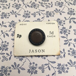May include: A brown button with a black rim, labelled "Jason" on a white card with the text "Here 2p Foreign 5d Each".