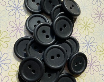 May include: A pile of 15 black plastic buttons with two holes each. The buttons are round and have a raised edge.