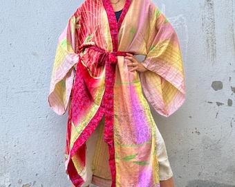 May include: A colorful, long kimono robe with a vibrant pattern of pink, red, yellow, and green. The robe is tied at the waist with a red sash. A straw hat is worn on the head.