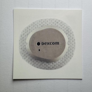 May include: A square, off-white sticker featuring a circular medical device with the word "dexcom" printed on it. The device is grey with a black dot and a smaller dot. The device is surrounded by a textured, dotted ring.