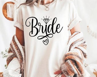 Puede incluir: Camiseta blanca con la palabra "Bride" en escritura negra con un gráfico de diamante sobre la palabra.