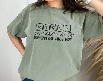 May include: A green t-shirt with the text "BIBLE reading HOMESCHOOL KINDA MOM" in black lettering. The word "BIBLE" is spelled out with individual letters in boxes.