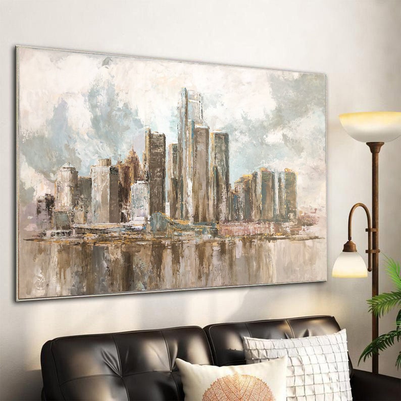 Neutral-toned abstract city skyline painting with skyscrapers and reflective water, displayed in a modern living room.