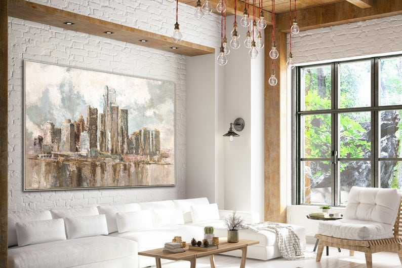 Neutral-toned abstract city skyline painting with skyscrapers and reflective water, displayed in a modern living room.