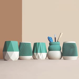 Può includere: Una collezione di cinque organizer da scrivania verde acqua e bianchi. Gli organizer presentano design geometrici e a coste. Uno degli organizer contiene forbici, una penna e una matita. Gli organizer sono realizzati in un materiale strutturato.