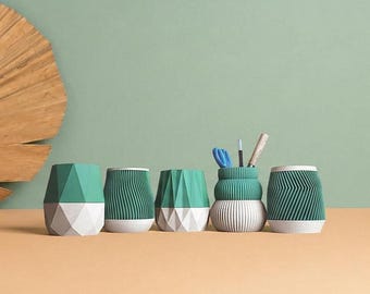 May include: Five small containers in shades of teal and white, featuring geometric and ribbed textures. One container holds a pair of blue scissors, a pencil, and a wooden tool. A large, dried, fan-shaped palm leaf is positioned to the left.
