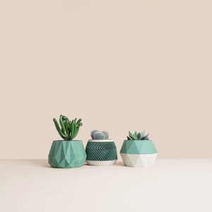 May include: Three geometric succulent planters in green and white. The planters are made of a textured material and have a modern design.