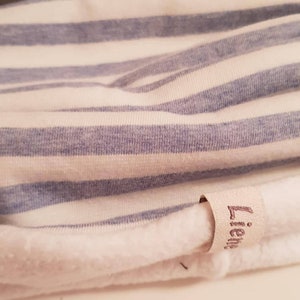 Puede incluir: Tela a rayas blancas y azules con una etiqueta blanca que dice "Lieb*" en cursiva.