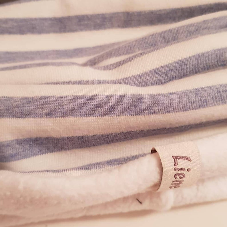 Puede incluir: Tela a rayas blancas y azules con una etiqueta blanca que dice "Lieb*" en cursiva.