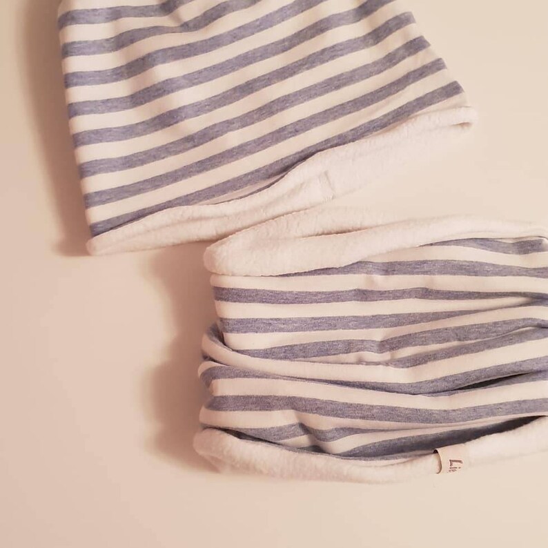 Puede incluir: Un cuello de cuello a rayas azules y blancas con forro de vell&oacute;n blanco. El cuello de cuello est&aacute; doblado por la mitad y tiene una peque&ntilde;a etiqueta blanca con la letra "L".