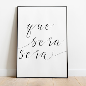 Könnte beinhalten: Schwarz-weiß gerahmter Druck mit dem Text "que sera sera" in kursiver Schrift.