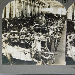 Puede incluir: Una foto estereoscópica vintage en blanco y negro de una planta de fábrica con filas de motores en proceso de montaje. La foto está etiquetada como "Keystone View Company, Copyrighted, Made in U.S.A., Manufacturers, Publishers".