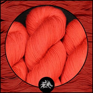 May include: Close-up of a bright orange yarn skein. The yarn is soft and fluffy, and it is perfect for knitting or crocheting.