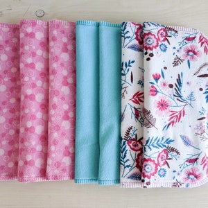 May include: Five fabric swatches, two pink with white polka dots, one light blue, and two white with pink and burgundy floral patterns.