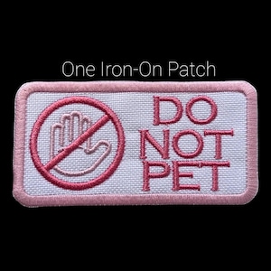 May include: A rectangular iron-on patch with a pink border and a white background. The patch features a pink hand inside a circle with a slash, and the words "DO NOT PET" in pink. The text "One Iron-On Patch" is above the patch.