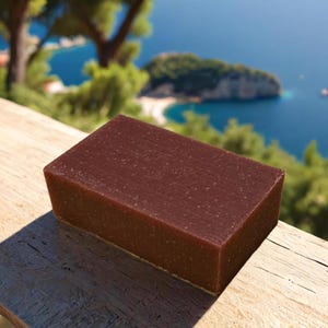 May include: A rectangular bar of dark brown soap with a grainy texture. The soap is sitting on a wooden surface.