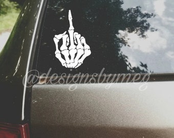 May include: A white skeleton hand giving the middle finger, on a black car window. The sticker says "@designsbymeg"