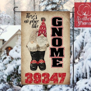 May include: A red and white gnome with a black hat and boots stands in front of a sign that says "There's no place like GNOME" with the number 39347 below. The sign is on a brown background with a white border.