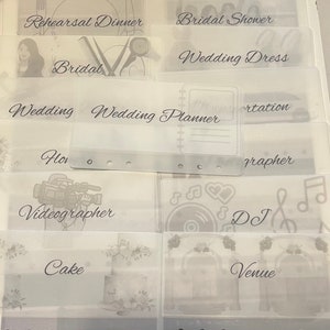 May include: A set of clear plastic dividers with labels for wedding planning. The labels include "Rehearsal Dinner", "Bridal Shower", "Wedding Dress", "Bridal", "Wedding", "Wedding Planner", "Photographer", "Videographer", "Cake", "Venue", "DJ", and "Flowers".