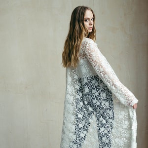 May include: A woman wearing a white lace maxi dress with long sleeves and black trousers. She is wearing burgundy platform heels and has long blonde hair.