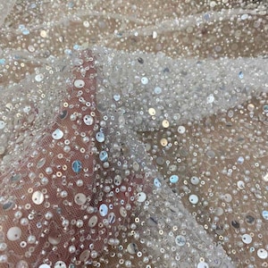 May include: White mesh fabric with small white pearls and silver sequins.