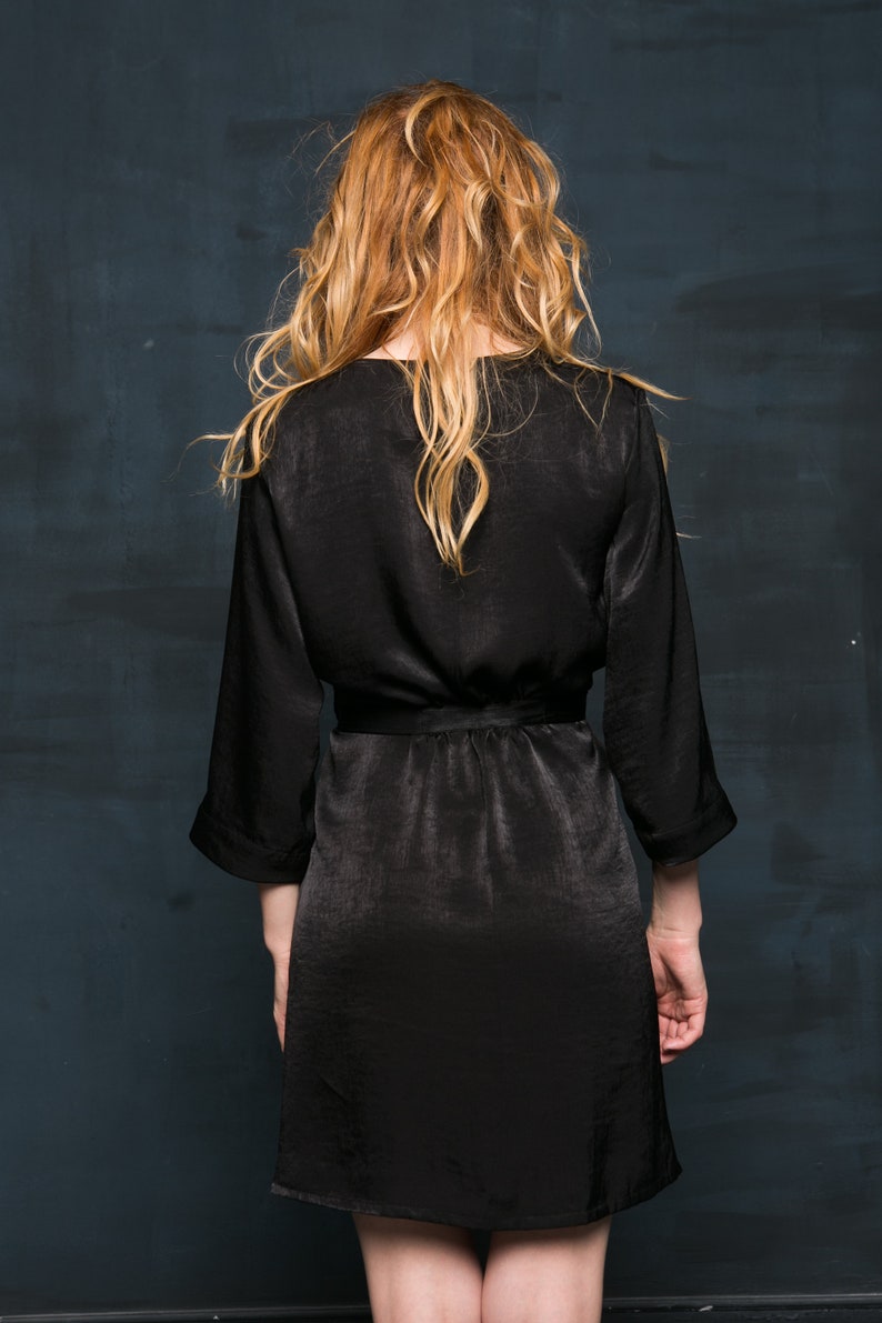 A black satin robe with long sleeves and a tie belt. The dressing gown is knee-length and has a simple, elegant design.