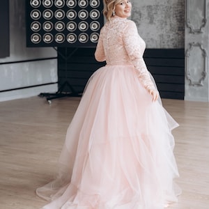 Blush lace long sleeve wedding top styled with layered tulle skirt, romantic bridal look.